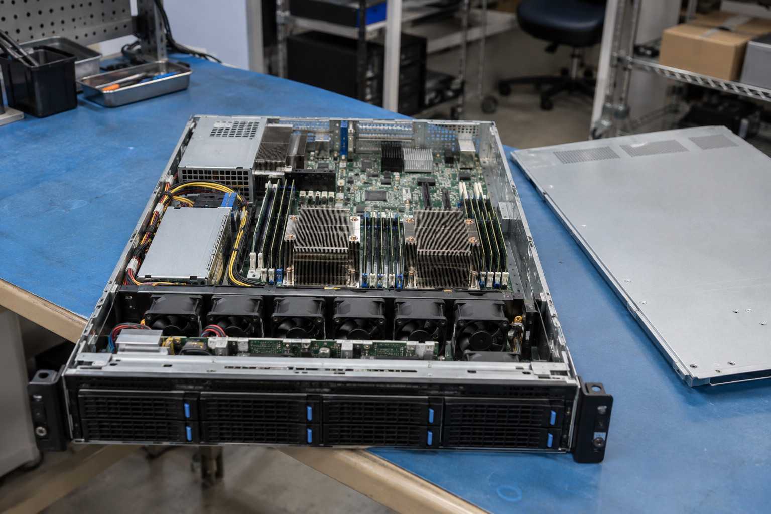 An open server chassis sits on a workbench in a technical workshop.